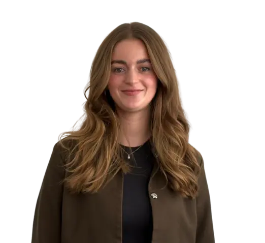 Vrouw met lang lichtbruin haar in donker shirt en bruine jas, glimlachend tegen een lichte achtergrond.
