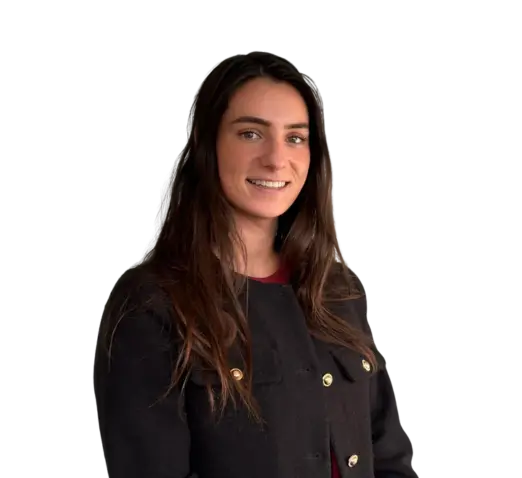 Vrouw met lang bruin haar in donker jasje, lachend tegen een lichte achtergrond.