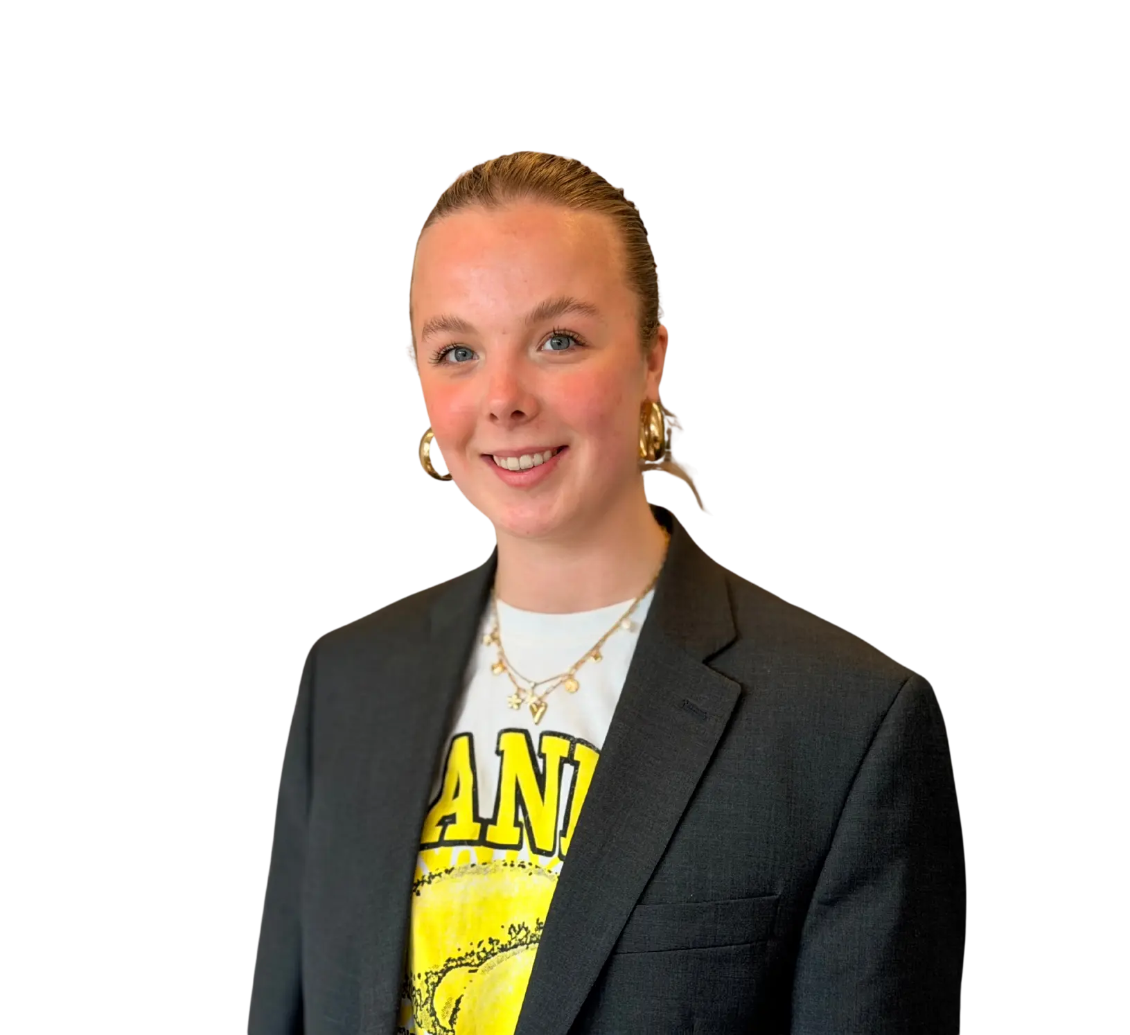 Vrouw met blond haar in knot in zwarte blazer en T-shirt met print, lachend en kijkend in de camera.