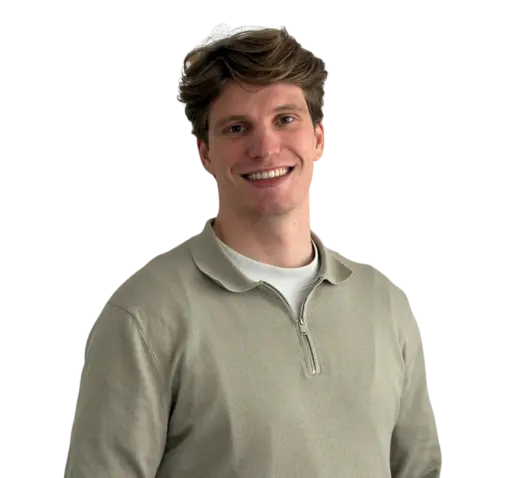 Man met kort bruin haar in beige trui, lachend tegen een lichte achtergrond.