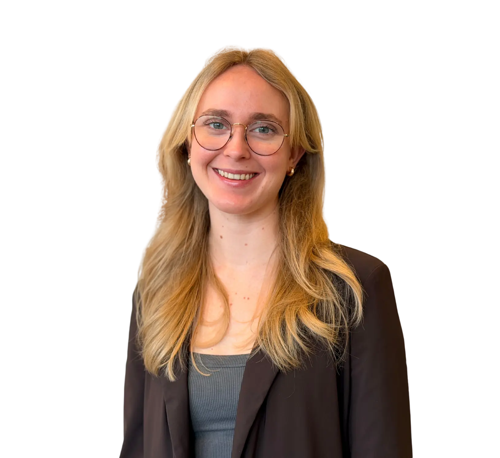 Vrouw met lang blond haar en bril in donkere blazer, glimlachend kijkend in de camera.