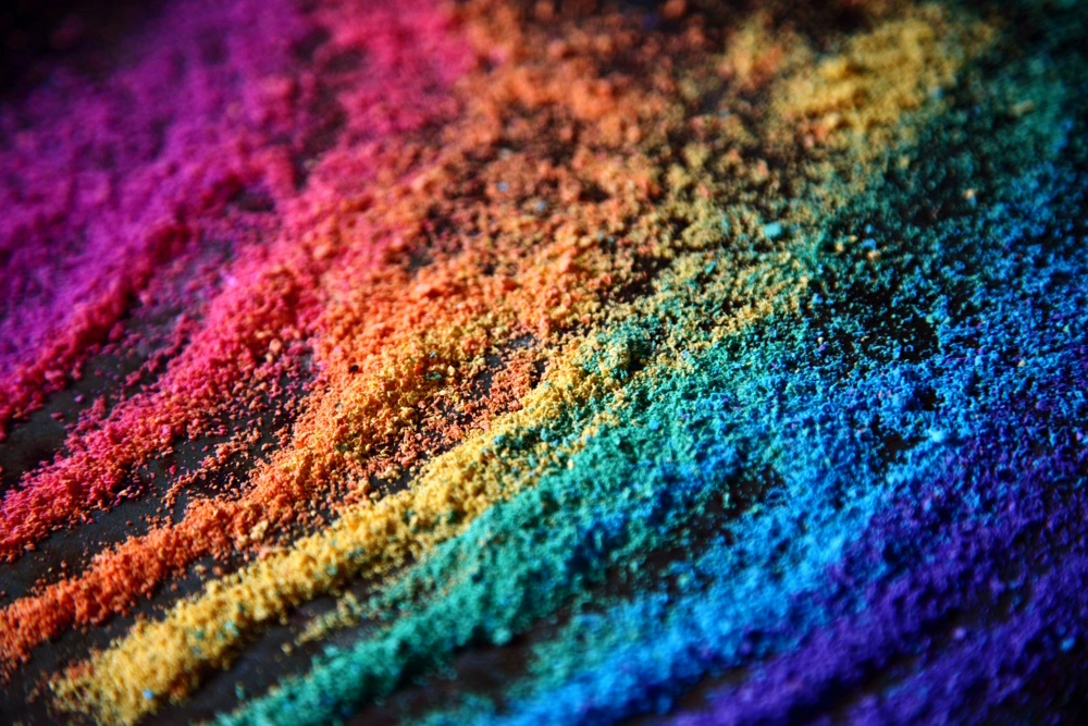 Gekleurde poeder in de kleuren van de regenboog ligt in strepen op een donker oppervlak.