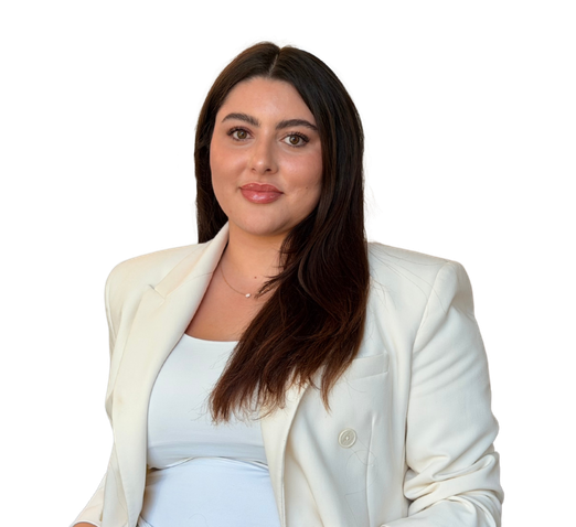 Vrouw met lang donker haar in crèmekleurige blazer, kijkend in de camera tegen een witte achtergrond.