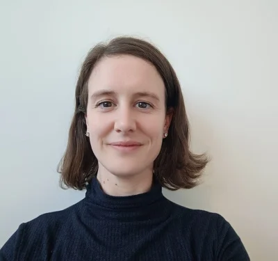 Lachende vrouw met kort bruin haar, met een zwarte coltrui aan.