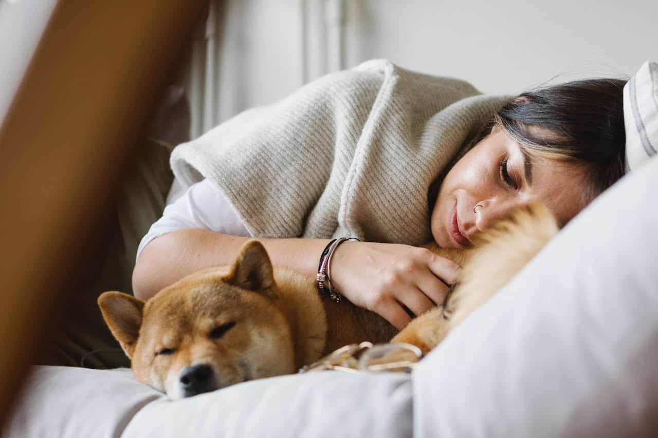 Vrouw slaapt met slapende hond tegen haar aan